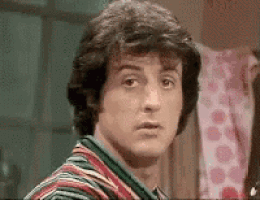 a man with curly hair is wearing a striped shirt and looking at the camera .