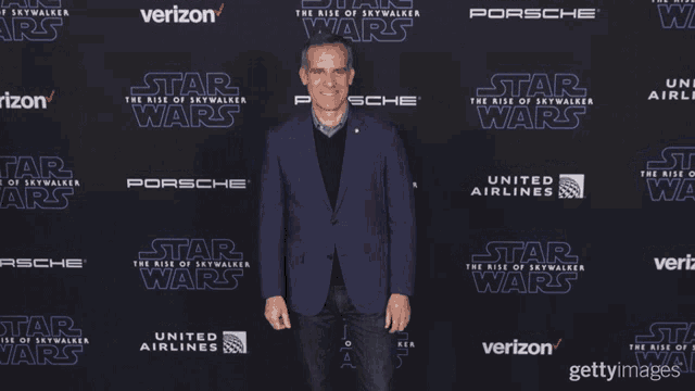 a man in a suit stands in front of a star wars poster
