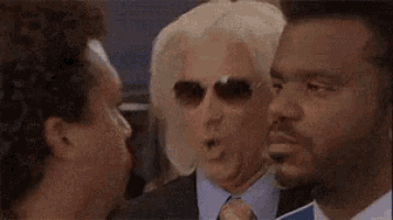 a group of men are standing next to each other and one of them is wearing sunglasses .