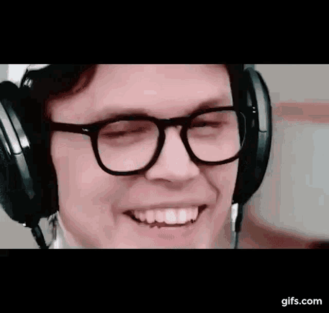 a man wearing glasses and headphones is smiling while listening to music .