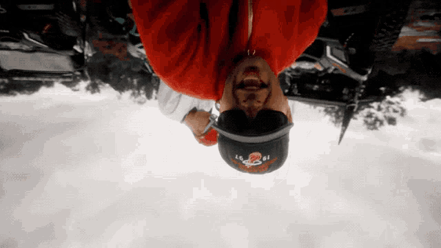 a man wearing a red hoodie and a hat with the number 2 on it is upside down