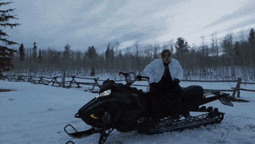 a man is sitting on a snowmobile in a snowy field