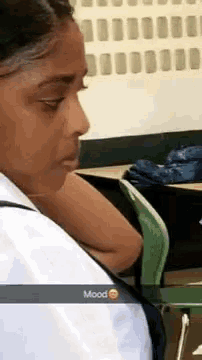 a woman is sitting at a desk in a classroom with a backpack on her back .