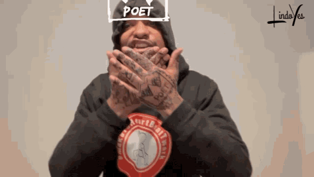 a man wearing a hoodie and a shirt that says ' poet ' on it is clapping his hands .