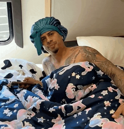 a man with a tattoo on his chest is laying in bed with a unicorn blanket