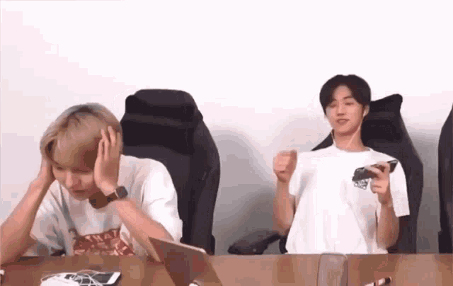 two men are sitting at a table playing a video game .