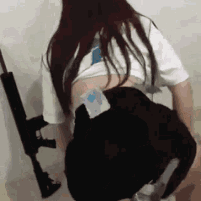 a woman is holding a gun in her hand while wearing a white shirt and black shorts .