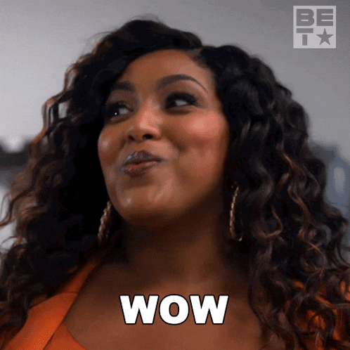a woman with curly hair is making a surprised face and the word wow is on her chest