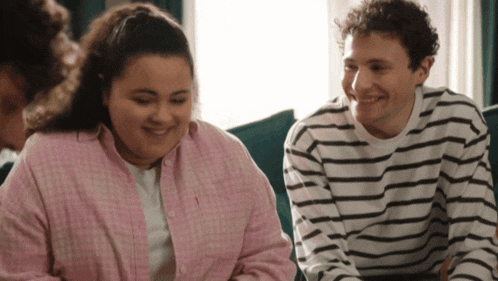 a man and a woman sit on a couch smiling