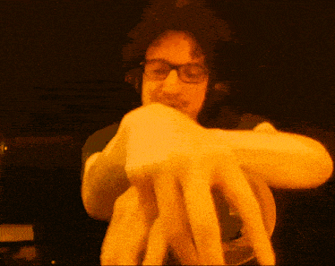 a man wearing glasses and headphones holds a yellow object in his hand