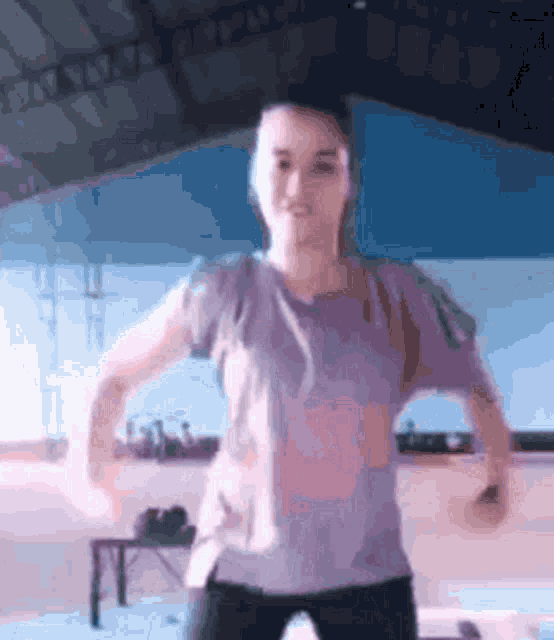 a woman in a purple shirt is dancing in a room with a blue ceiling .