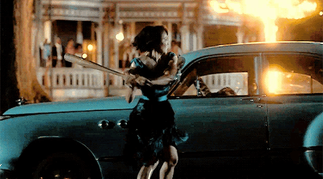 a woman holding a baseball bat standing next to a car