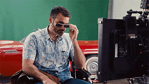 a man wearing sunglasses is sitting in front of a monitor