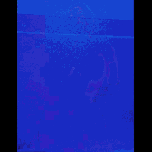a woman is standing in front of a blue wall holding something in her hands .