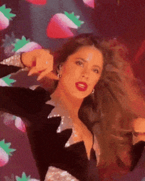 a woman in a black and silver dress is dancing with strawberries in the background