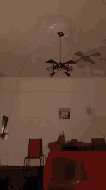 a woman with long black hair is standing in a dark room with a ceiling fan in the background .