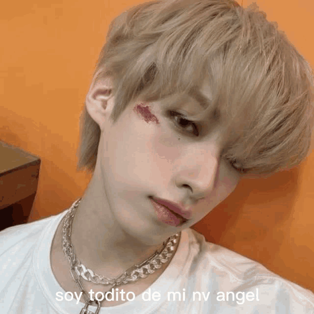a young man wearing a necklace and a white shirt with the words soy todito de mi nv angel above him