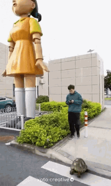 a turtle is walking in front of a large doll