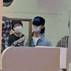 a man wearing a mask and a baseball cap is sitting in a cubicle .