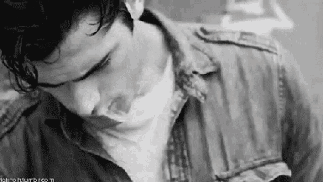 a black and white photo of a man wearing a denim jacket .