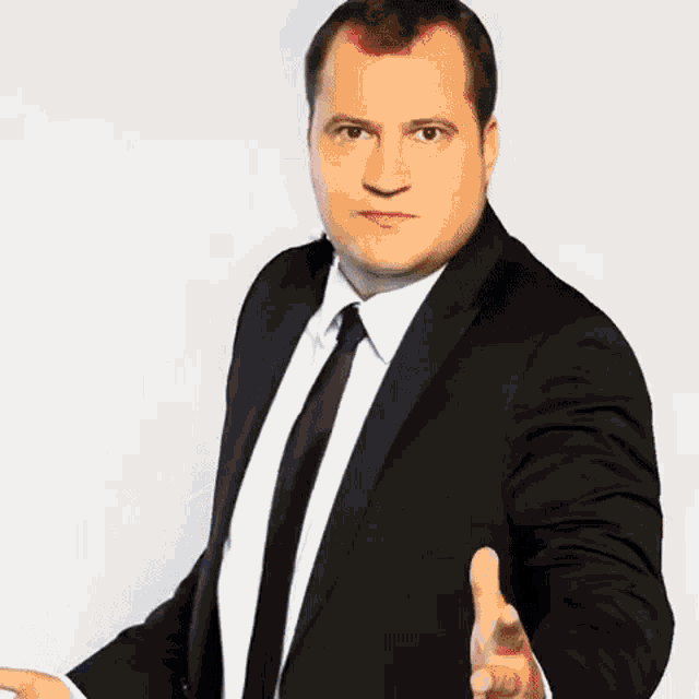 a man in a suit and tie is reaching out his hand for a handshake
