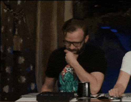 a man with glasses and a beard sits at a table