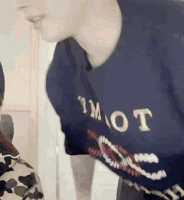 a man wearing a blue t-shirt with the word mot on it is standing next to a woman .