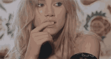 a woman is holding her finger to her lips .