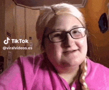 a woman wearing glasses and a braided wig is smiling .