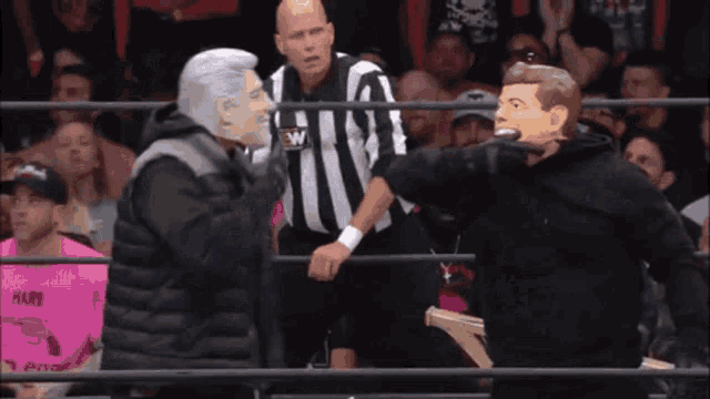 a man in a mask is fighting another man in a wrestling ring while a referee watches .