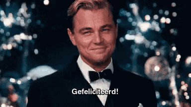 a man in a tuxedo and bow tie is smiling and says gefeliciteerd