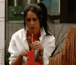 a woman in a white shirt is smoking a red bong