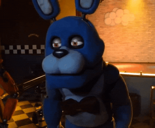 a blue stuffed animal with a bow tie is standing in a room