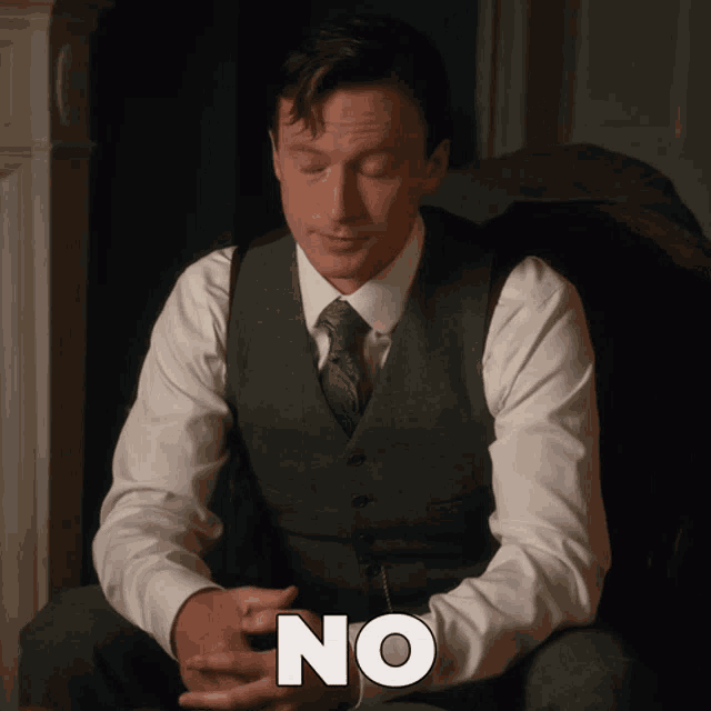 a man in a suit and tie is sitting in a chair with his eyes closed and the word no written on his arm