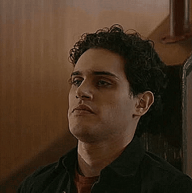 a close up of a man 's face with a black jacket on .
