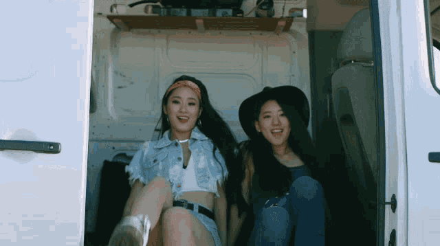 two asian women sit in the back of a white van