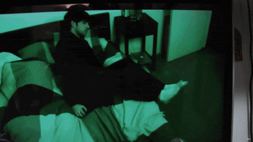 a tv screen shows a man laying on a bed with a green background