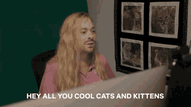 a man in a pink shirt says hey all you cool cats and kittens in front of a computer