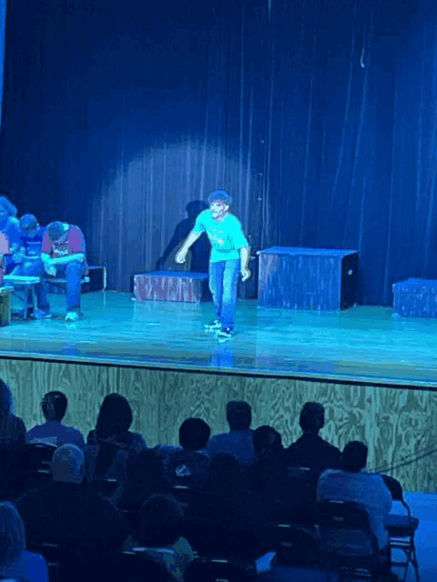 a boy in a green shirt is standing on a stage in front of a blue curtain