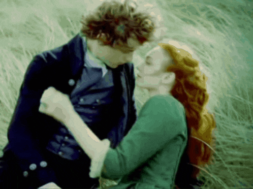 a man and woman are kissing in a field