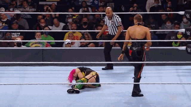 two women are wrestling in a ring with a referee
