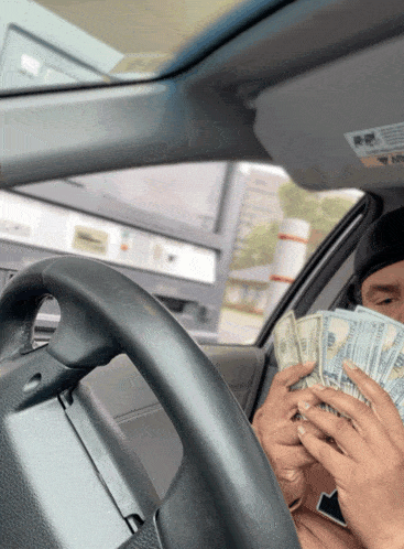 a man in a car is holding a stack of money