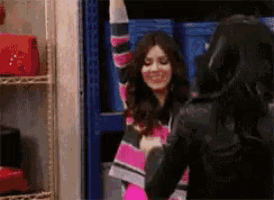 a woman in a pink and black striped sweater is standing next to another woman