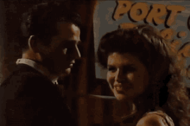 a man and woman are looking at each other in front of a sign that says " port "