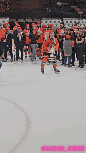 a hockey player holds up a trophy in front of a crowd