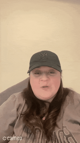 a woman wearing a ny hat and a cameo logo on her shirt