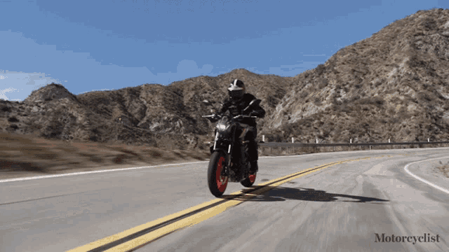 a person riding a motorcycle on a road with mountains in the background and the word motorcyclist at the bottom