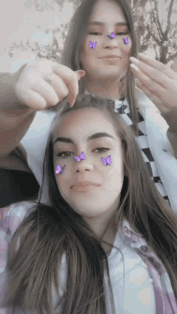 two girls with purple butterflies on their faces pose for a picture