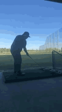 a man is swinging a golf club at a golf ball in a driving range .