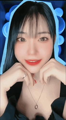 a woman wearing a necklace and a ring is smiling